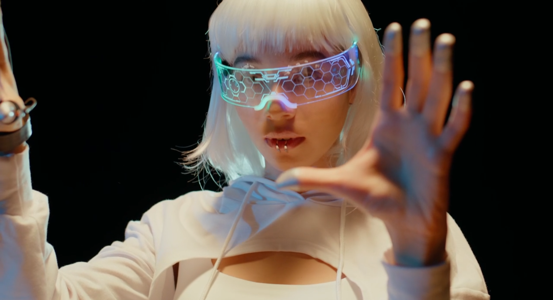 A young woman wearing futuristic VR glasses focuses on an unseen task making subtle movements with her hads